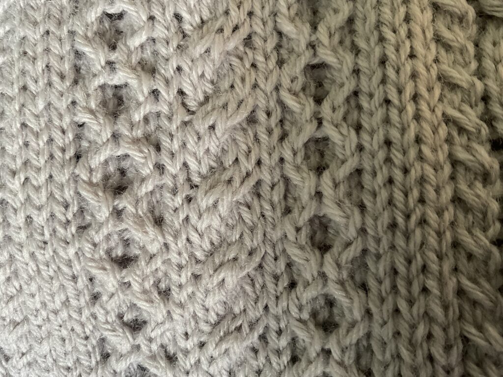 Close up of various Aran stitches on knitted biker style coatigan