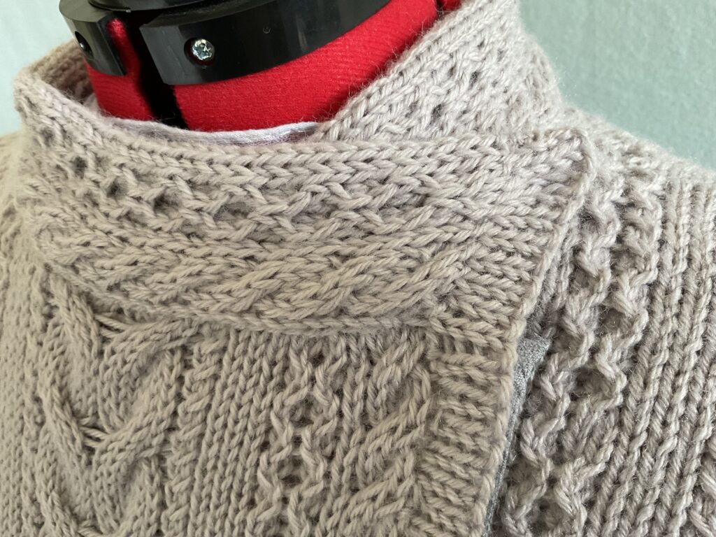 Close up image of coatigan stand up collar and some Aran stitches in the biker coatigan