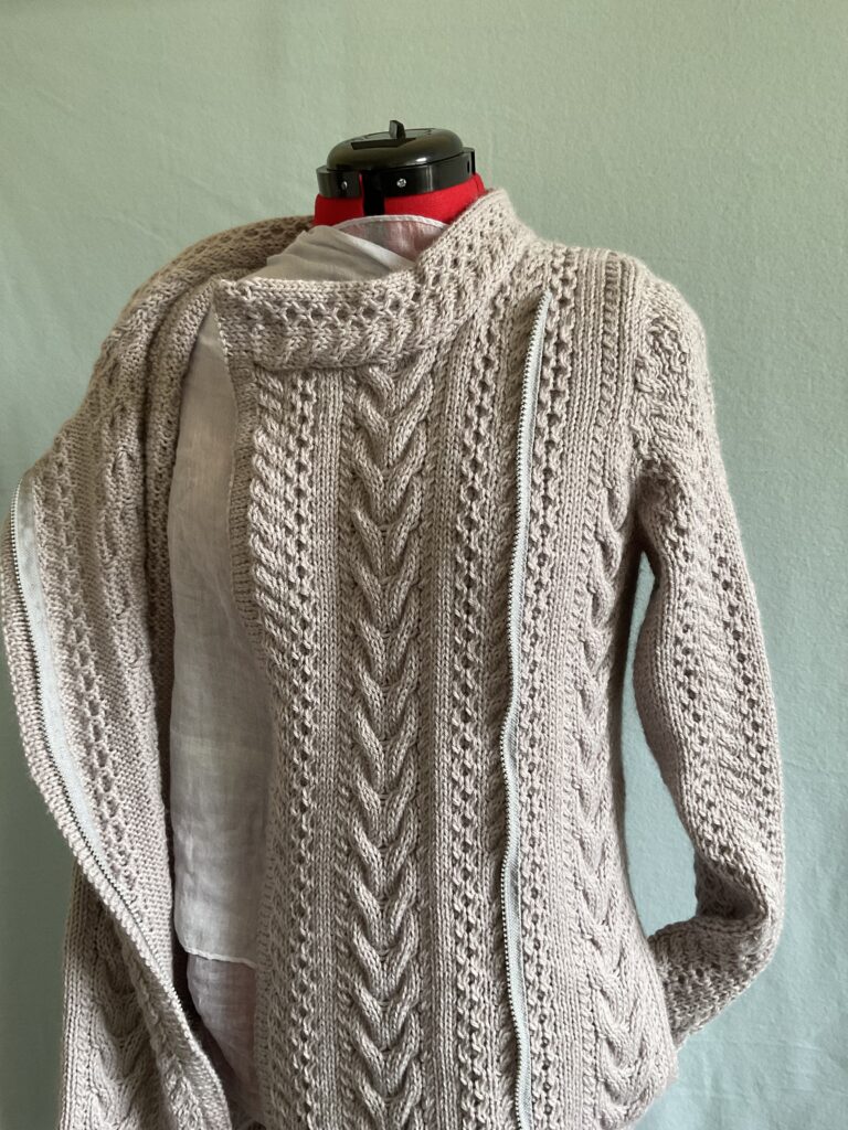 View of knitted biker style coatigan with  multiple Aran stitches and zipper open 