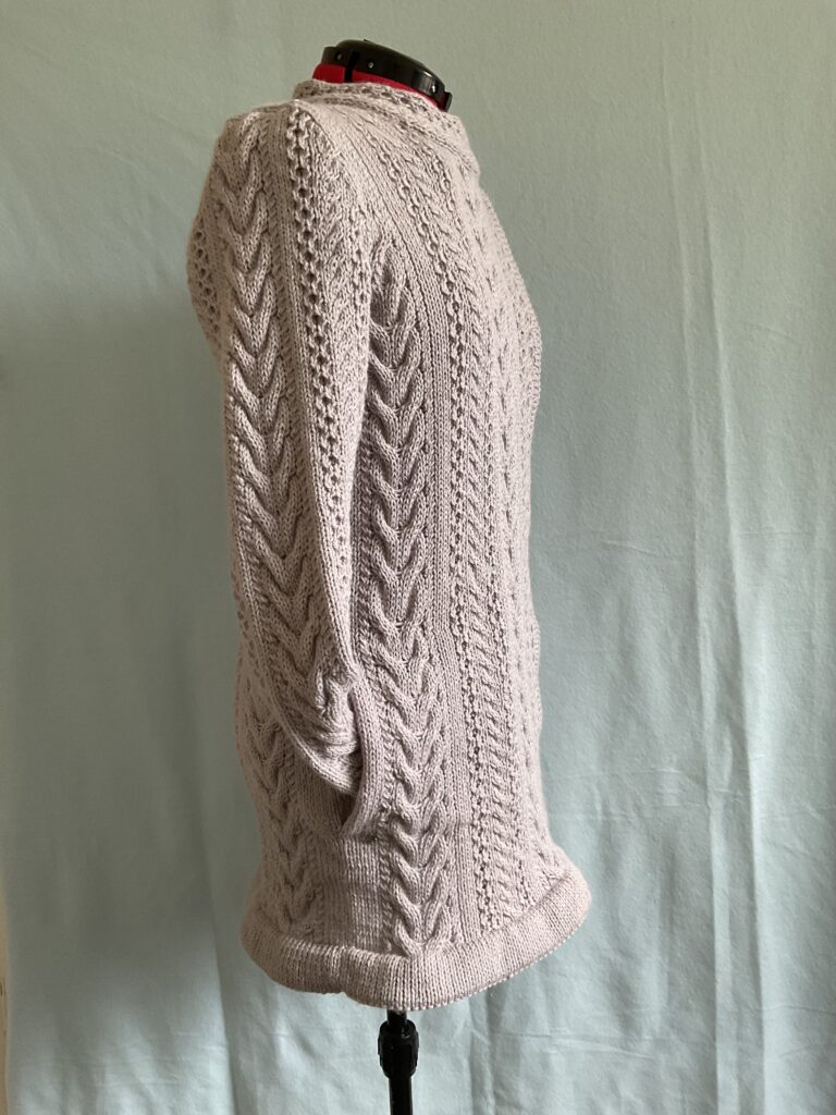 Side view of knitted biker style ladies coatigan featuring multiple Aran stitch patterns