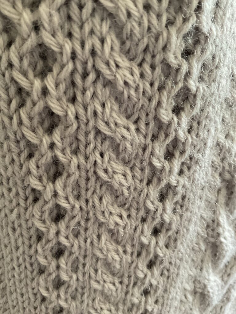 Close up of various Aran stitches on knitted biker style coatigan